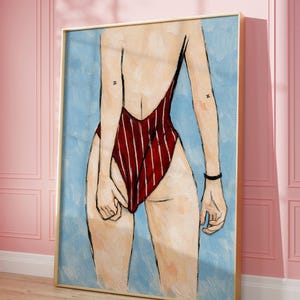 Könnte beinhalten: Ein künstlerisches Gemälde einer Person von hinten, die einen rot-weiß gestreiften Badeanzug trägt. Das Kunstwerk ist in einem goldfarbenen Rahmen gerahmt und vor einem hellblauen Hintergrund platziert. Die Person hat ein schwarzes Armband und ein Tattoo des Buchstabens "Z" auf dem Arm.