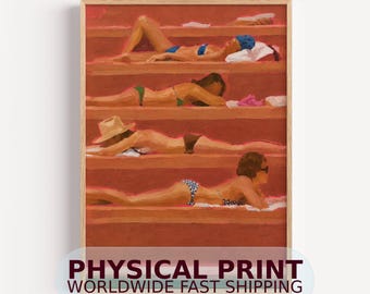 May include: A framed art print depicting four figures lying on terracotta-colored steps. The figures wear various swimsuits, including blue, green, and patterned designs, with one figure wearing a straw hat, all resting on white towels.