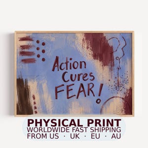 Könnte beinhalten: Ein rechteckiger Kunstdruck in einem hellen Holzrahmen mit einem abstrakten Hintergrund aus blauen, beigen und dunkelroten Pinselstrichen. Der Text "Action Cures FEAR!" steht in der Mitte in einer dunkelroten, handgeschriebenen Schrift.