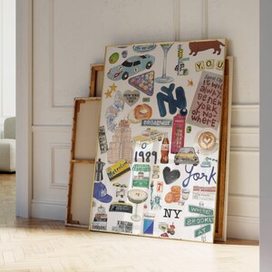 Op de afbeelding: Een rechthoekige ingelijste wandkunstprint met een collage van illustraties in New York City-thema, waaronder een gele taxi, een rode telefooncel, een bagel, een kopje koffie, het Vrijheidsbeeld en de tekst Broadway, 1989 en New York.