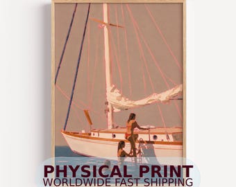 May include: A framed art print depicting a white sailboat on calm water with two figures in red swimwear. One figure stands on the deck near the mast, while the other is partially submerged in the water. The scene features soft lighting and a muted palette.