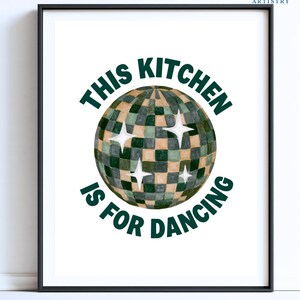 May include: A framed wall art print featuring a disco ball with a checkered pattern in shades of dark green and beige. The text THIS KITCHEN IS FOR DANCING is printed in dark green capital letters, arching above and below the disco ball graphic.