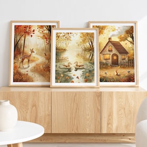 Peut inclure: Trois impressions encadrées à l'aquarelle représentant des scènes d'automne. L'une représente un cerf dans une forêt, une autre des canards sur un étang, et la troisième une maison de campagne. Les cadres sont marron clair, avec des tons chauds.