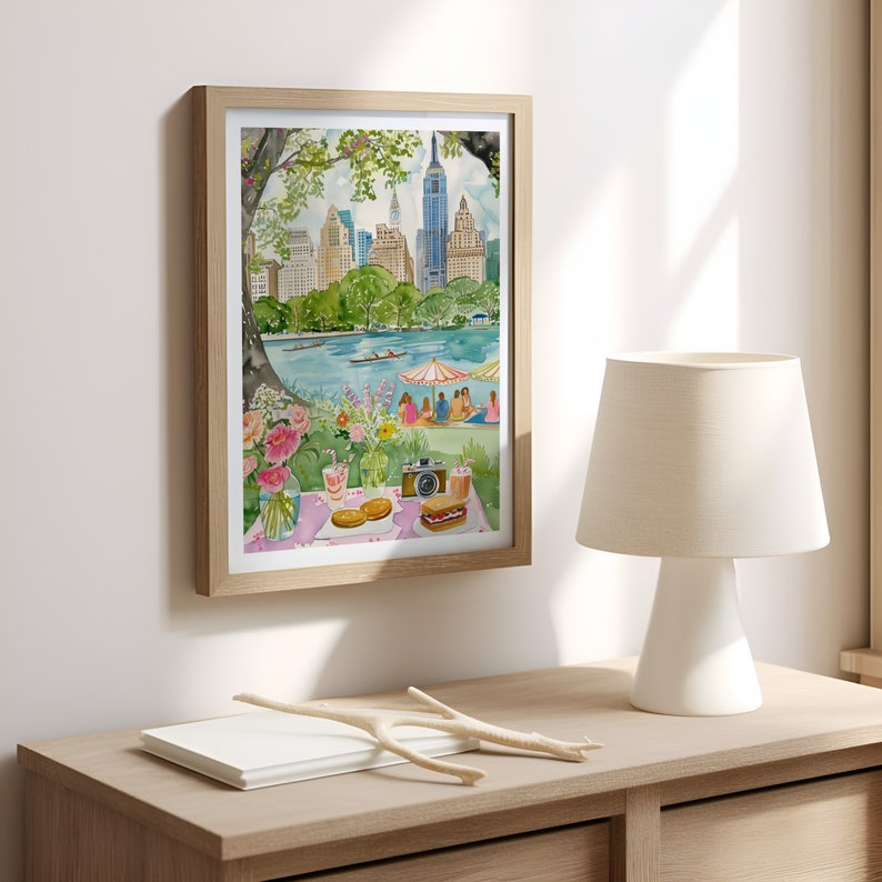 May include: A watercolor painting of a picnic in Central Park, New York City. The painting features a group of people sitting on a blanket under a tree, with the city skyline in the background. There are sandwiches, drinks, and a camera on the blanket.