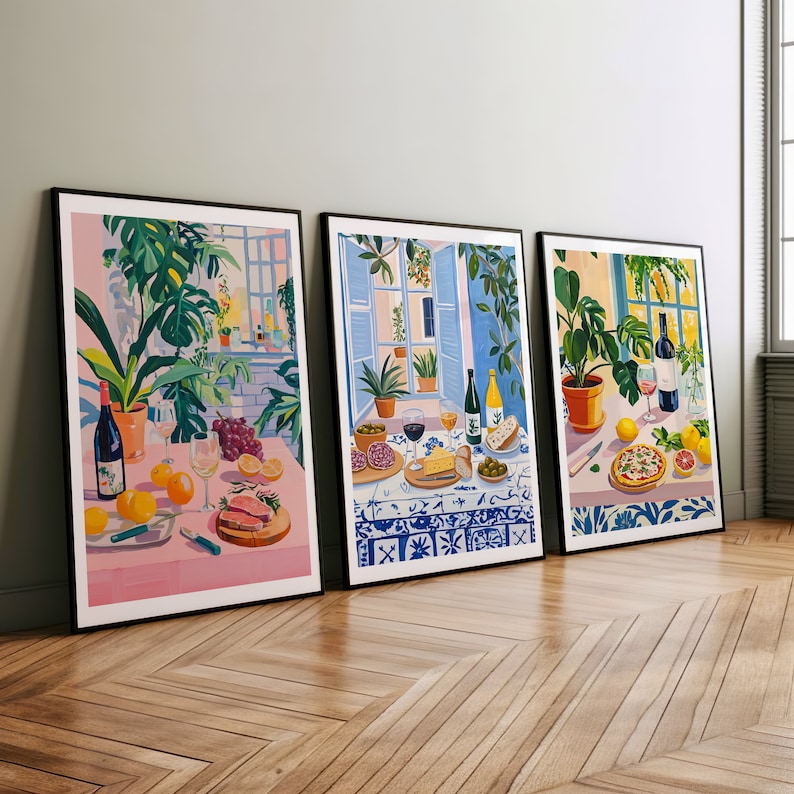 Puede incluir: Tres ilustraciones enmarcadas de escenas de bodeg&oacute;n con comida y vino. La primera imagen presenta un mantel rosa con una copa de vino, uvas, naranjas y un plato de comida. La segunda imagen presenta una superficie de azulejos azules y blancos con una copa de vino, una botella de vino, queso, pan y aceitunas. La tercera imagen presenta una superficie de azulejos azules y blancos con un plato de pizza, una botella de vino y una copa de vino.