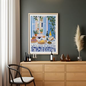 Puede incluir: Una pintura de una ventana con vista a un patio con una mesa puesta con copas de vino, botellas de vino, queso, pan y aceitunas. La pintura est&aacute; enmarcada y colgada en una pared de una habitaci&oacute;n con un armario de madera y una cortina blanca.