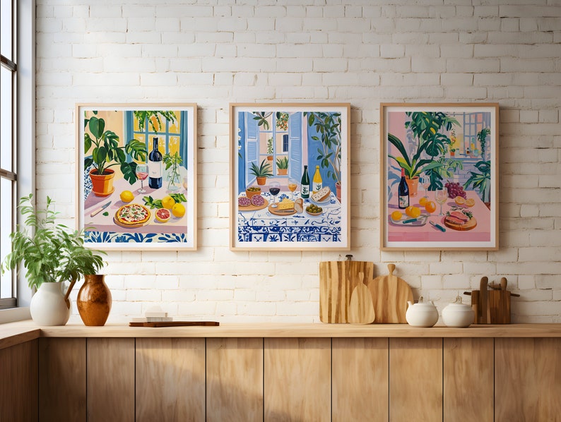 Puede incluir: Tres ilustraciones enmarcadas de escenas de bodeg&oacute;n con comida, vino y plantas. Cada ilustraci&oacute;n presenta una paleta de colores diferente: rosa, azul y amarillo. Las ilustraciones est&aacute;n colgadas en una pared de ladrillo blanco.