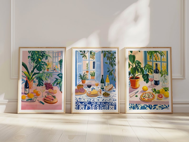 Puede incluir: Tres impresiones enmarcadas de bodegones que representan una mesa puesta con comida, vino y plantas. La primera impresi&oacute;n muestra una mesa rosa con una botella de vino tinto, uvas, naranjas y un plato de comida. La segunda impresi&oacute;n muestra una mesa de azulejos azules y blancos con una botella de vino blanco, una botella de vino tinto, queso, pan, aceitunas y una copa de vino. La tercera impresi&oacute;n muestra una mesa rosa con una botella de vino tinto, una copa de vino, limones y una pizza.