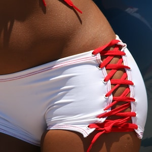 May include: White bikini bottoms with red laces. The laces are tied in a criss-cross pattern on the side of the hips.