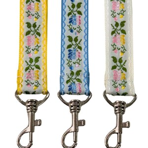 May include: Three colourful ribbon lanyards with floral patterns. Each lanyard has a silver swivel hook.