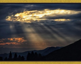 May include: A dramatic sunset over a mountain range with a bright, golden cloud and sun rays breaking through dark clouds.