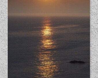 May include: A sunset over the ocean with the sun reflecting off the water. The sun is a bright yellow and the water is a dark blue.
