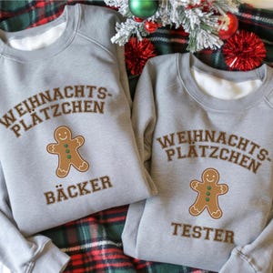 Puede incluir: Dos sudaderas grises con el texto "WEIHNACHTS-PLÄTZCHEN" y un gráfico de hombre de jengibre. Una dice "BÄCKER" y la otra "TESTER". Ropa festiva de vacaciones.