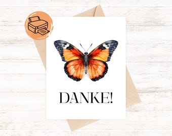 May include: A white card with a watercolor butterfly design in shades of orange, black, and yellow. The word "DANKE!" is printed in black. The card is on a kraft paper envelope.