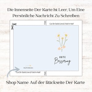May include: A light blue card with a white daisy and bandage design. The card says "Gute Besserung" which means "Get Well Soon" in German. The card is blank inside for writing a personal message. The back of the card has a space for a shop name.