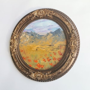 May include: An oval oil painting depicting a mountain landscape with orange flowers in a decorative, gold-toned frame. The sky features blue and purple tones. The painting is created in an impressionistic style.