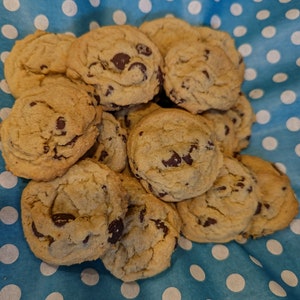 May include: A blue and white polka dot plate filled with chocolate chip cookies. The cookies are golden brown and have chocolate chips throughout.