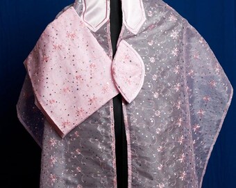 May include: A sheer, gray prayer shawl with pink satin trim and floral embroidery. The shawl features a matching pink pouch and a decorative collar. The design includes small, sparkling embellishments.