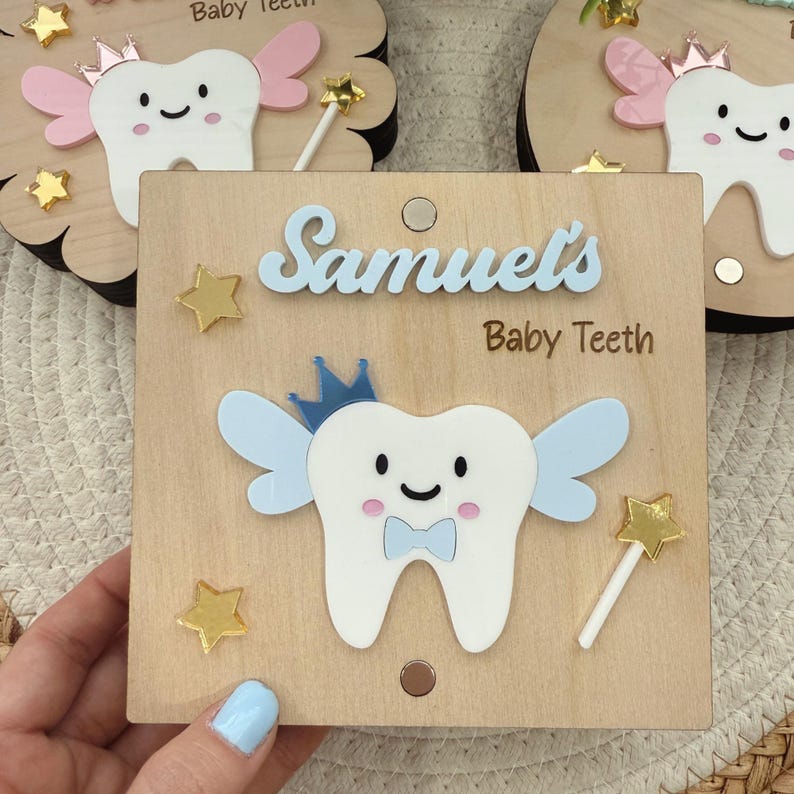 May include: A wooden box with a blue tooth fairy design, a blue bow, and gold stars. The box is labeled "Samuel's Baby Teeth".