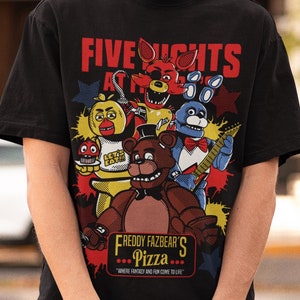 Peut inclure: Un t-shirt noir avec un imprimé graphique de personnages du jeu vidéo "Five Nights at Freddy's". Le graphique représente Freddy Fazbear, Bonnie le Lapin, Chica la Poule, Foxy le Renard Pirate et un cupcake. Le texte "Freddy Fazbear's Pizza" est imprimé sous le graphique.
