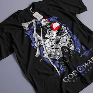 May include: Black t-shirt featuring a graphic of characters from the video game "God of War: Ragnarök." The design includes a bearded warrior with a red mark and a young archer, with the game's title in white and blue.