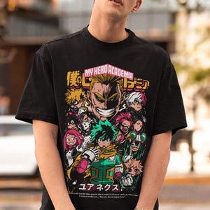 May include: Black t-shirt with a graphic print of characters from the anime My Hero Academia. The graphic includes the text "My Hero Academia" and Japanese characters. The characters are depicted in a colorful, action-packed style.