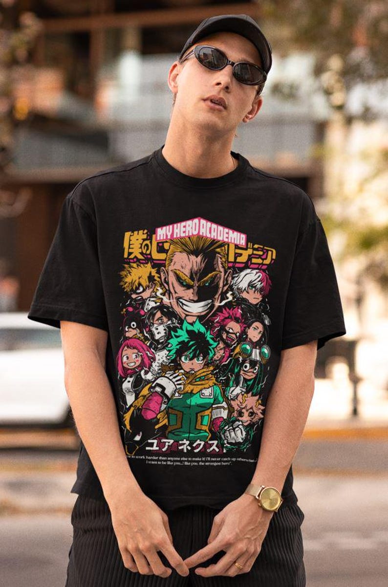May include: Black t-shirt with a graphic print of characters from the anime My Hero Academia. The graphic includes the text "My Hero Academia" and Japanese characters. The characters are depicted in a colorful, action-packed style.