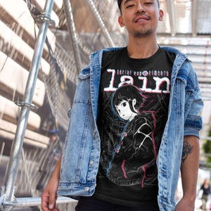 May include: A black t-shirt with a white and red graphic print of a girl with short black hair. The text "serial experiments lain" is printed in white and red on the shirt.