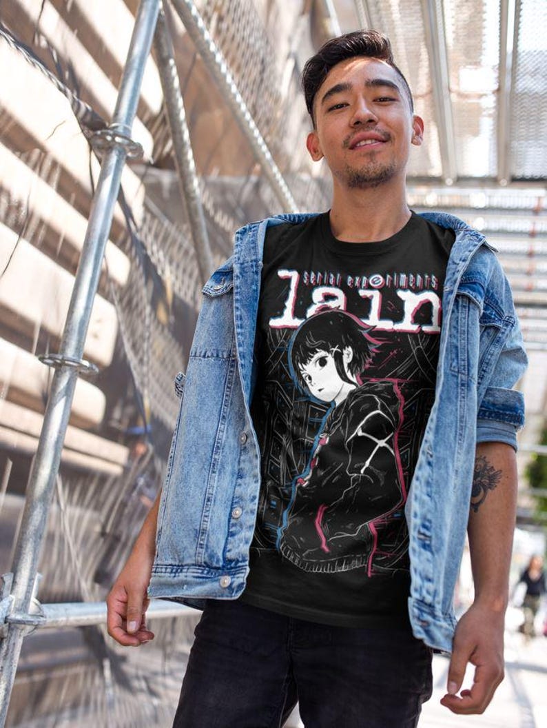 May include: A black t-shirt with a white and red graphic print of a girl with short black hair. The text "serial experiments lain" is printed in white and red on the shirt.