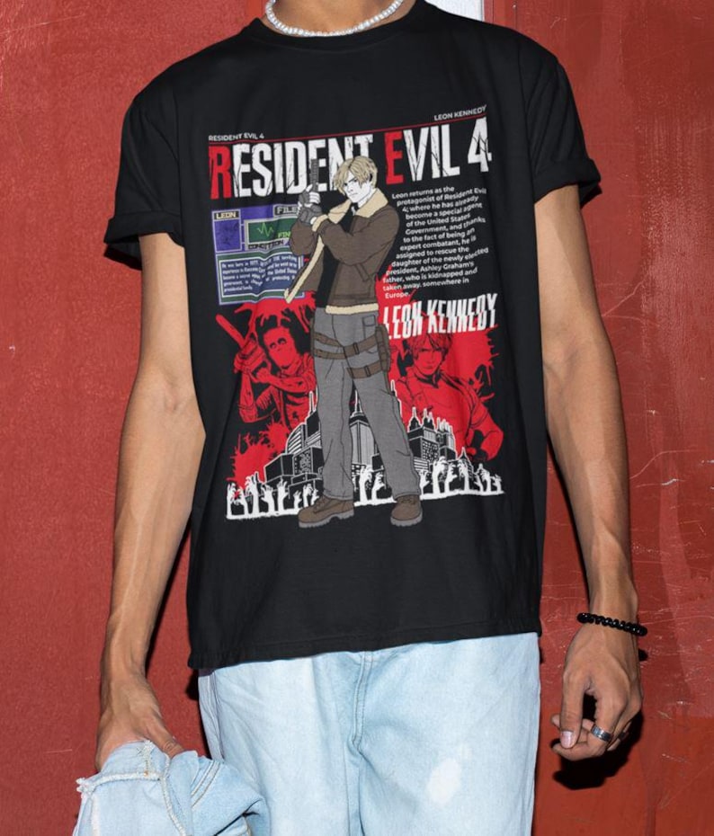 May include: Black t-shirt featuring a graphic print of a video game character holding a gun. The text "Resident Evil 4" is printed in white on the shirt. The character is standing in front of a city skyline. The text "Leon Kennedy" is printed in white at the bottom of the shirt.