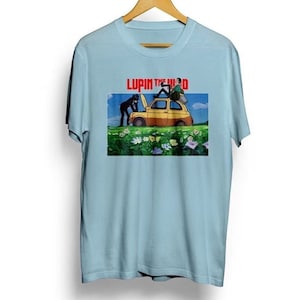 May include: Light blue t-shirt with a graphic print of a yellow car with two figures in black standing next to it. The text "Lupin the 3rd" is printed in red above the image.