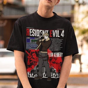 May include: Black t-shirt featuring a graphic print of Leon Kennedy from Resident Evil 4. The graphic includes the game's title, a character portrait, and text describing the game's story.