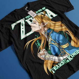 May include: Black t-shirt with a green and white graphic of Zelda from the Legend of Zelda: Tears of the Kingdom video game. The graphic features Zelda with blonde hair and a blue and gold outfit.