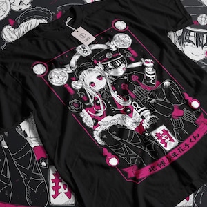 May include: Black t-shirt featuring a pink and white illustration of two anime characters. The characters are a girl with long white hair and a boy with black hair. The text "地縛少年花子くん" is written in pink at the bottom of the shirt.