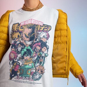 May include: White t-shirt with a graphic print of characters from the anime My Hero Academia. The graphic features the text "My Hero Academia" and Japanese characters. The characters are depicted in a colorful, comic book style.