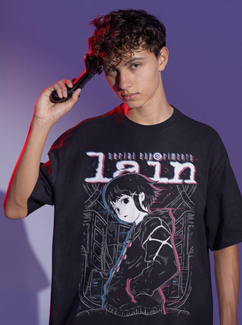 May include: Black t-shirt with a graphic print of a girl with black hair and a black jacket. The text "serial experiments lain" is printed in white on the shirt.