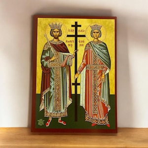 May include: A religious icon depicting two figures in royal attire, standing on either side of a cross. The figures are wearing crowns and holding a scepter and a book. The background is a gold color with a green border. The text on the cross reads "O' aip' n'ia Kwn'ti' ele' n'q".