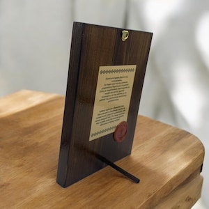 Back side of a handmade natural wood icon with silkscreen print on canvas, featuring a description of the crafting technique and a quality seal.