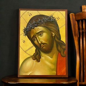 Può includere: Un'icona dipinta a mano che raffigura Gesù Cristo con una corona di spine. L'icona è dipinta in uno stile bizantino tradizionale con uno sfondo dorato e una veste rossa. L'icona è incorniciata in una cornice di legno.