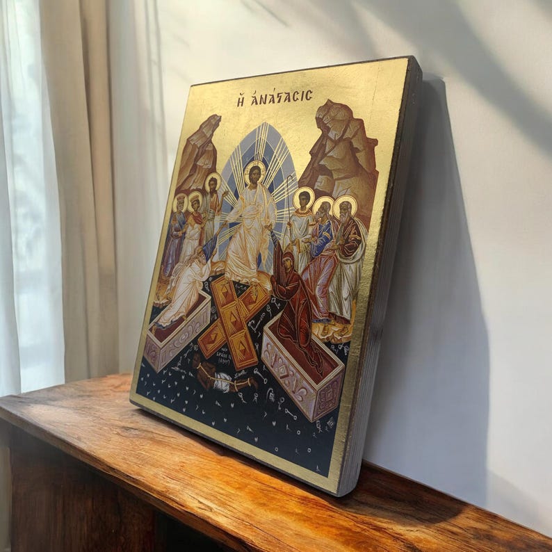 May include: A religious icon featuring a depiction of the resurrection. The artwork showcases figures in robes, a central figure with a halo, and the Greek text "H ANASTASIC" at the top. The background is gold with a dark blue base.