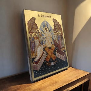 May include: A religious icon featuring a central figure in white robes, surrounded by others in various colors. The background includes mountains, a blue arched window, and the Greek text "H ANASTASIC". The artwork is on a gold-edged wooden panel.