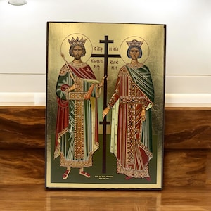 May include: A gold-leaf icon depicting two figures in royal attire, standing on either side of a cross. The figures are wearing crowns and holding scrolls. The icon is inscribed with Greek text.