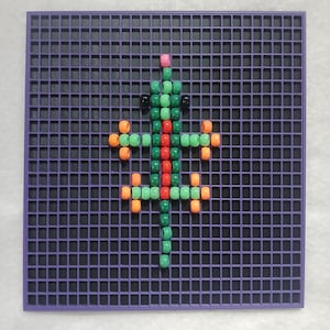 May include: A colorful lizard design made with small beads on a purple pegboard. The lizard features green, red, orange, and black beads, with a pink bead at the top. The pegboard has a grid pattern.