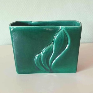 以下が含まれることがあります： 葉のデザインが施された緑色のセラミック製のプランター。プランターは長方形で、滑らかで光沢のある仕上げです。