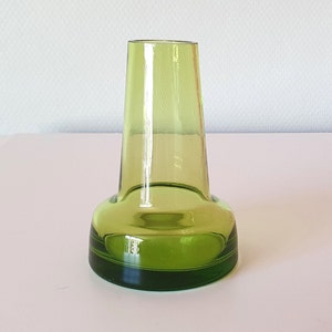 Pode incluir: Um pequeno vaso de vidro verde com uma base larga e um pescoço estreito.