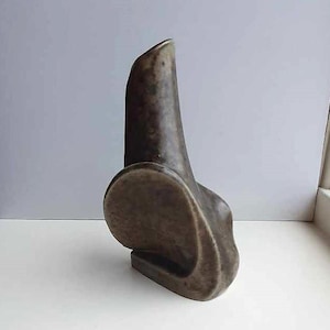 Op de afbeelding: Een bruine keramische vaas met een abstracte, organische vorm. De vaas heeft een hoge, smalle hals en een brede, ronde basis.