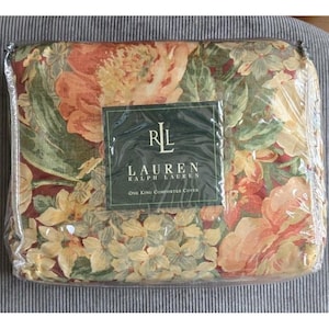 May include: A new Ralph Lauren King comforter cover in plastic packaging. The cover features a floral pattern in shades of orange, yellow, and green on a dark red background. The packaging includes a label with the Ralph Lauren logo.