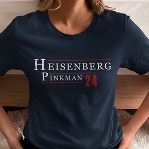 May include: A navy blue t-shirt with white text that reads "Heisenberg Pinkman 24" and the smaller text "Stay.  My.  White.  Trash.  Science."