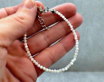 May include: A white beaded bracelet with a silver clasp.