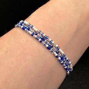 May include: A multi-strand bracelet made of blue and white beads. The bracelet is layered and has a delicate, minimalist design.
